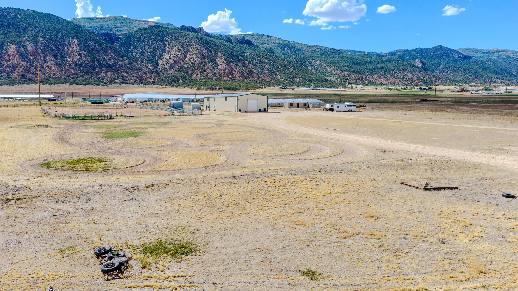 Expansive property featuring multiple outbuildings, a large metal-sided structure, and a dirt road entrance