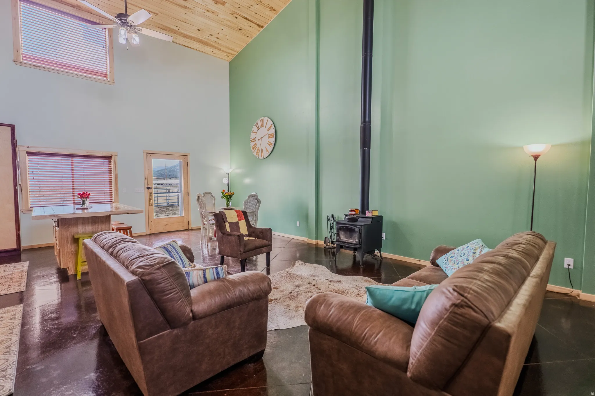 Vaulted wood-paneled ceiling, exposed wood beams, built-in wood-burning stove, high-set window, and polished concrete flooring
