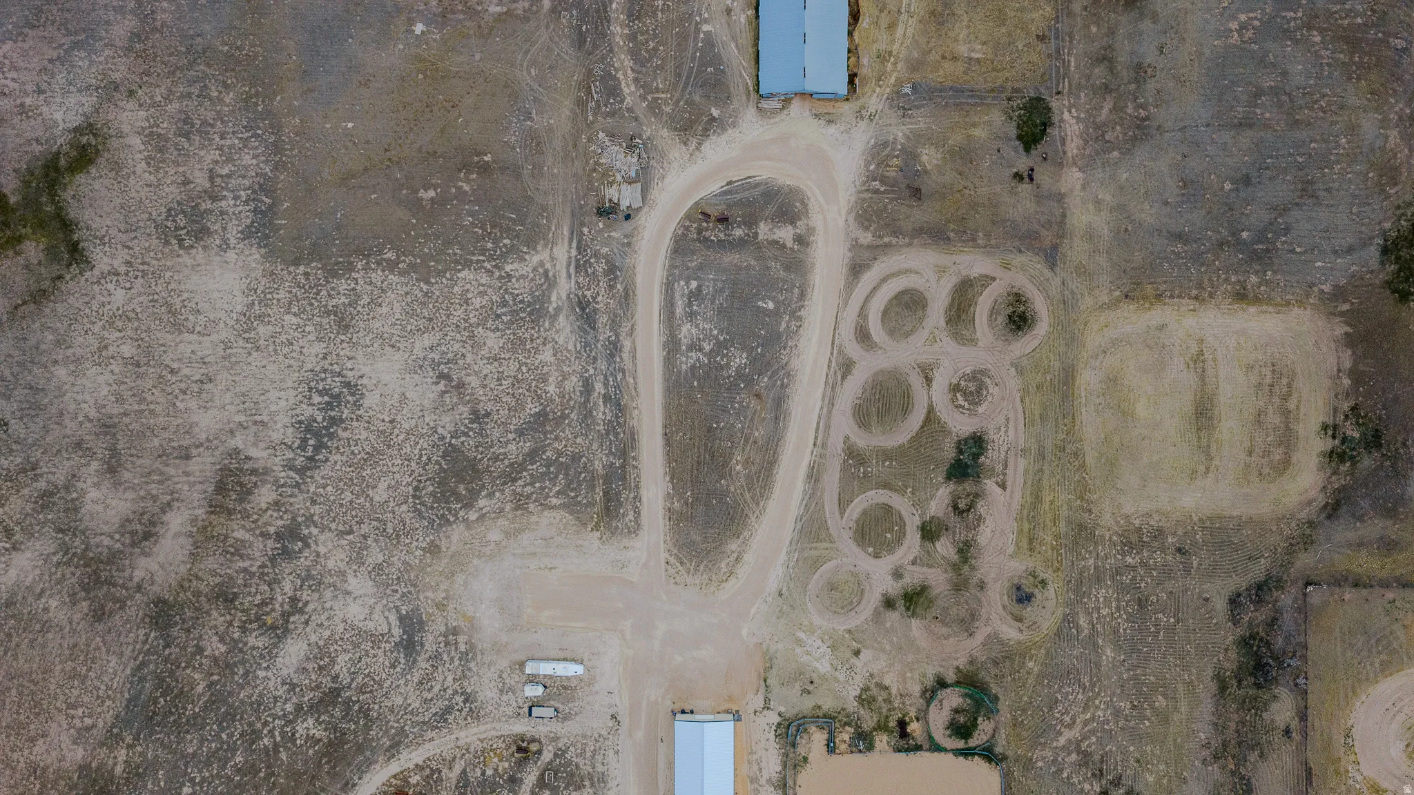 Expansive land featuring multiple outbuildings, dirt track, and varied terrain