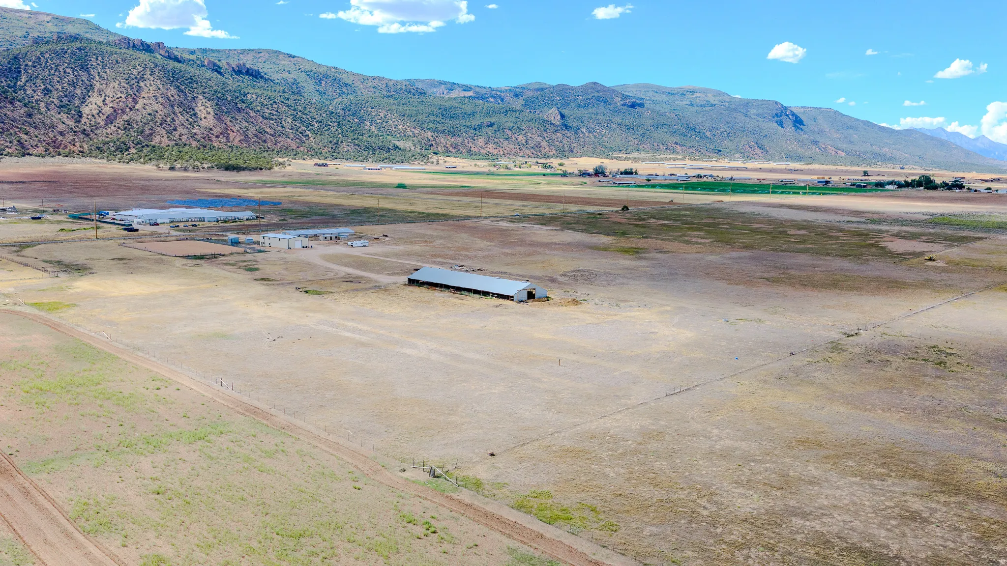 Expansive open land with a large agricultural building and distant mountain scenery