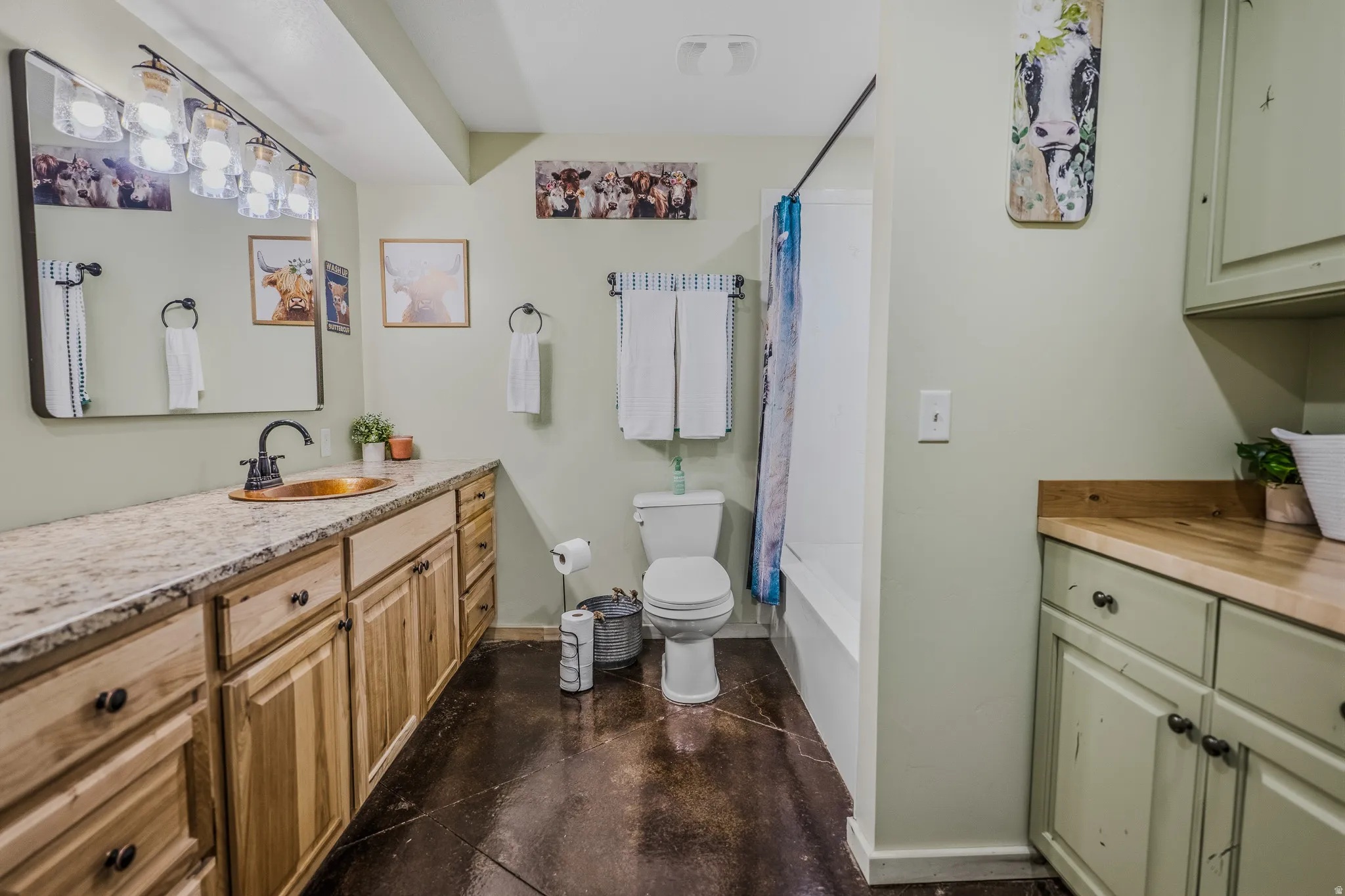 Extended vanity with natural wood-finish cabinetry, a copper basin sink, and a black-finish faucet
