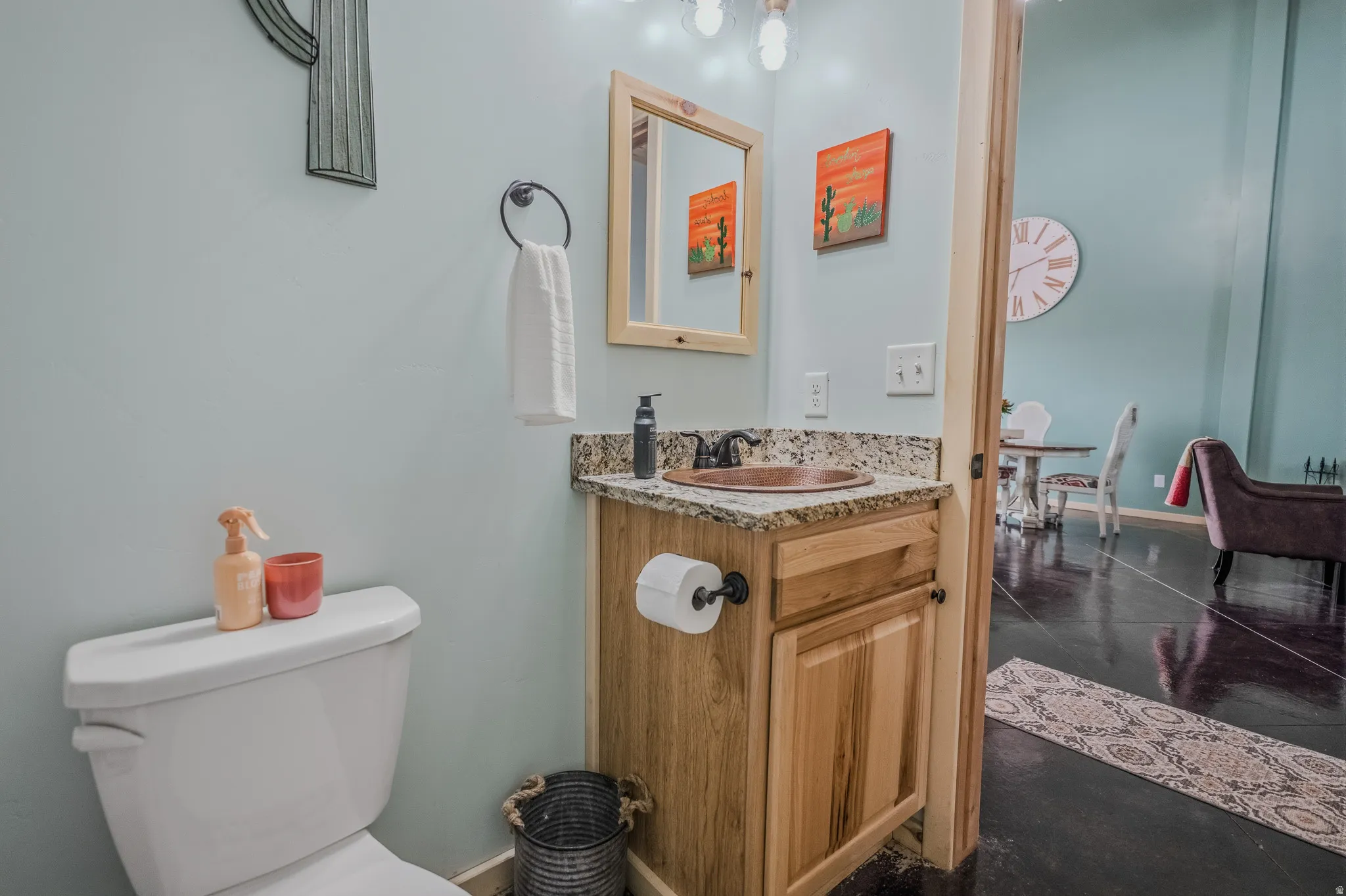 Wood vanity with a granite countertop, copper vessel sink, and a wood-framed mirror