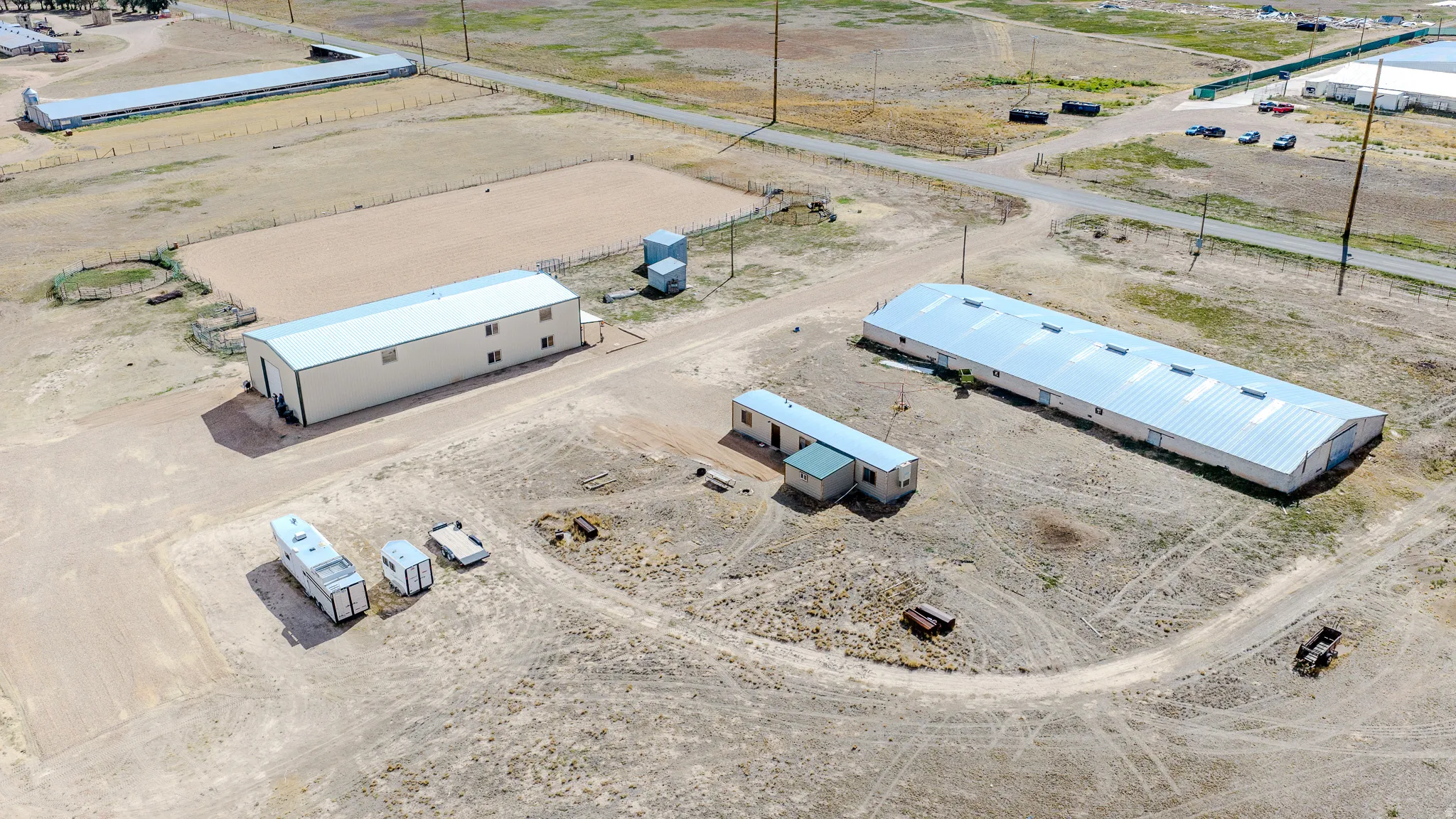 Extensive property featuring multiple large metal buildings, an open-air riding arena, and a smaller modular structure