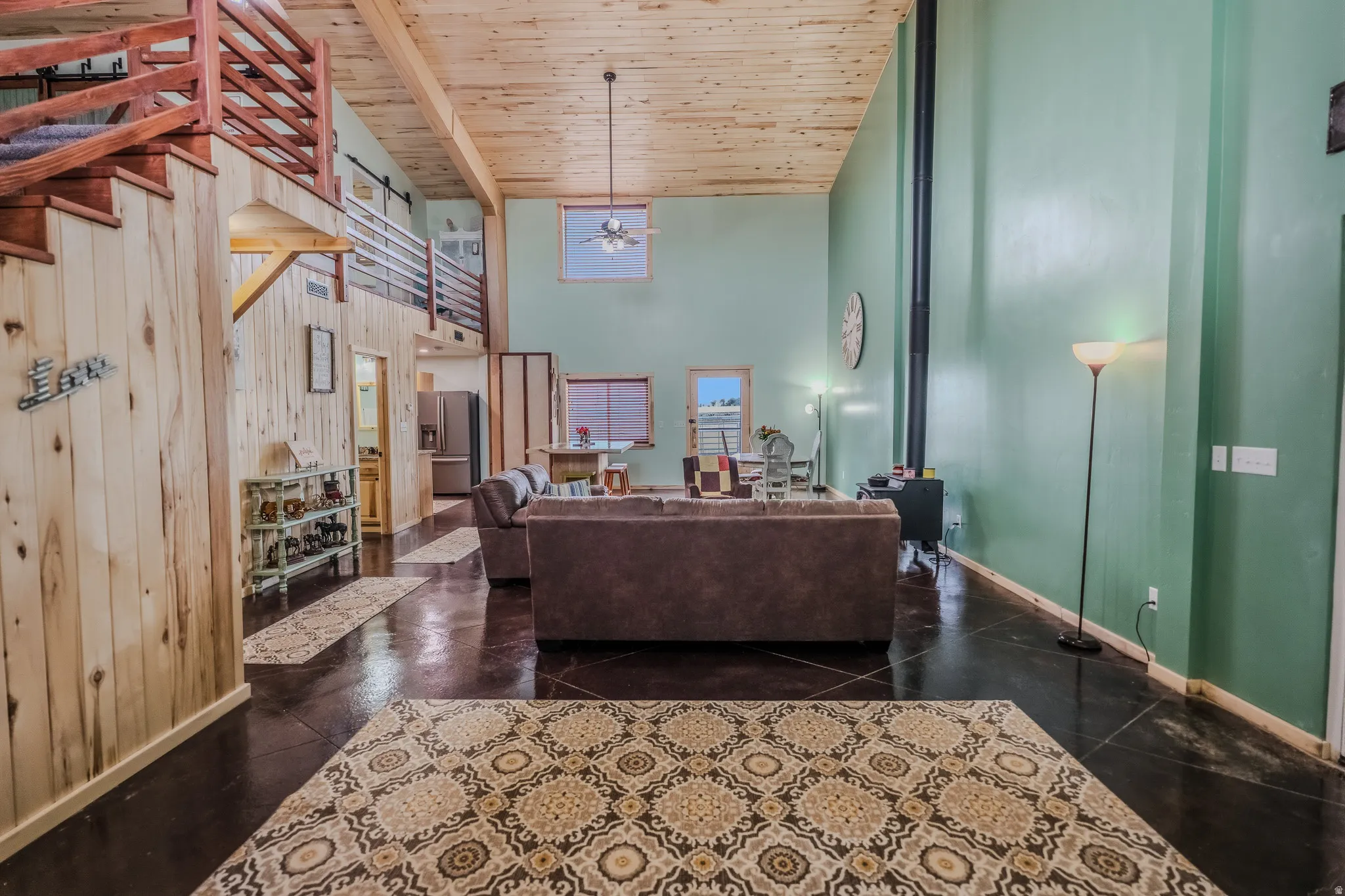 Vaulted wood-paneled ceiling, exposed wood staircase, wood plank wall finishes, and dark concrete flooring