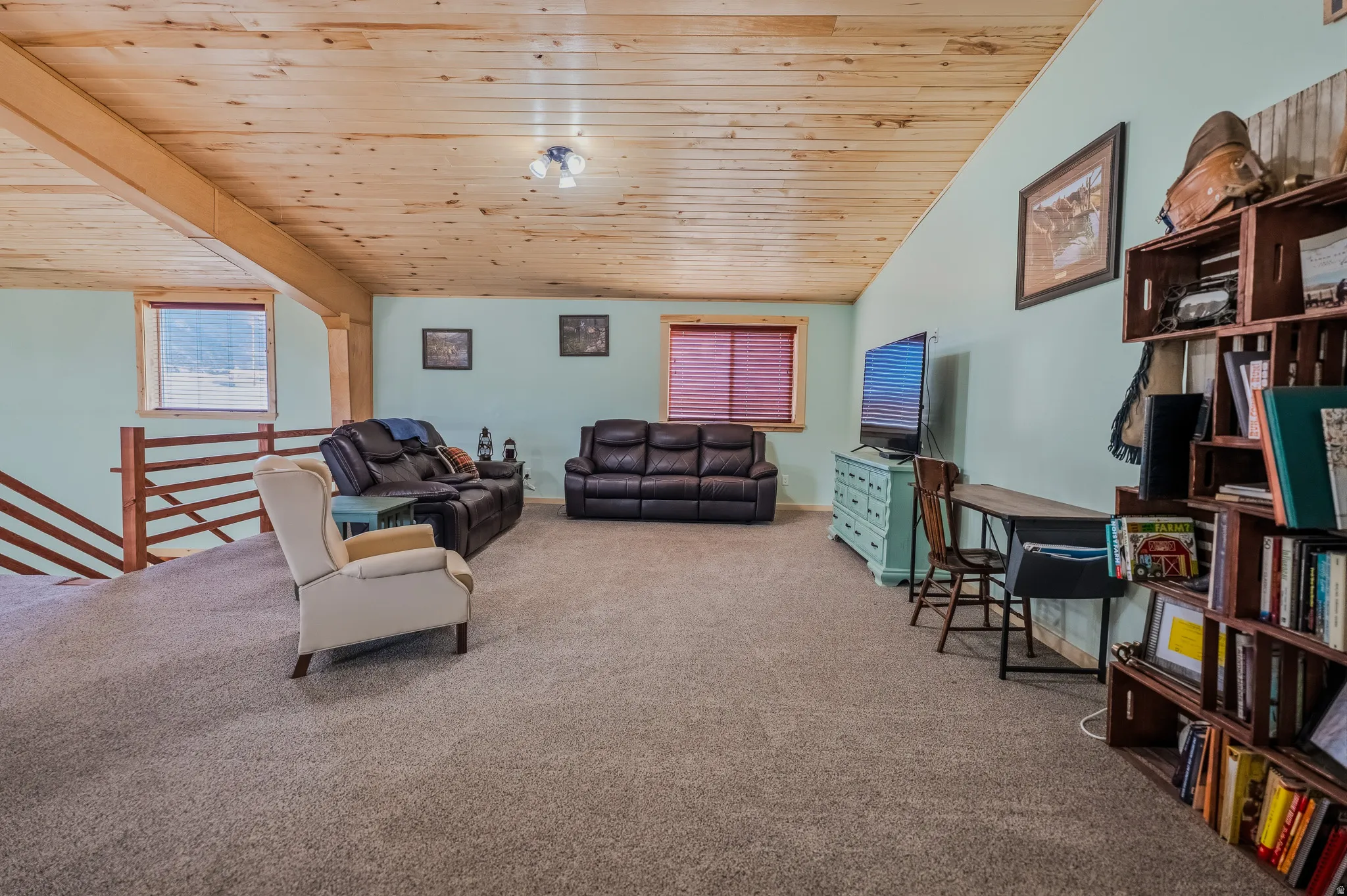Vaulted wood-paneled ceiling with exposed beams, light blue wall paint, and carpeted flooring