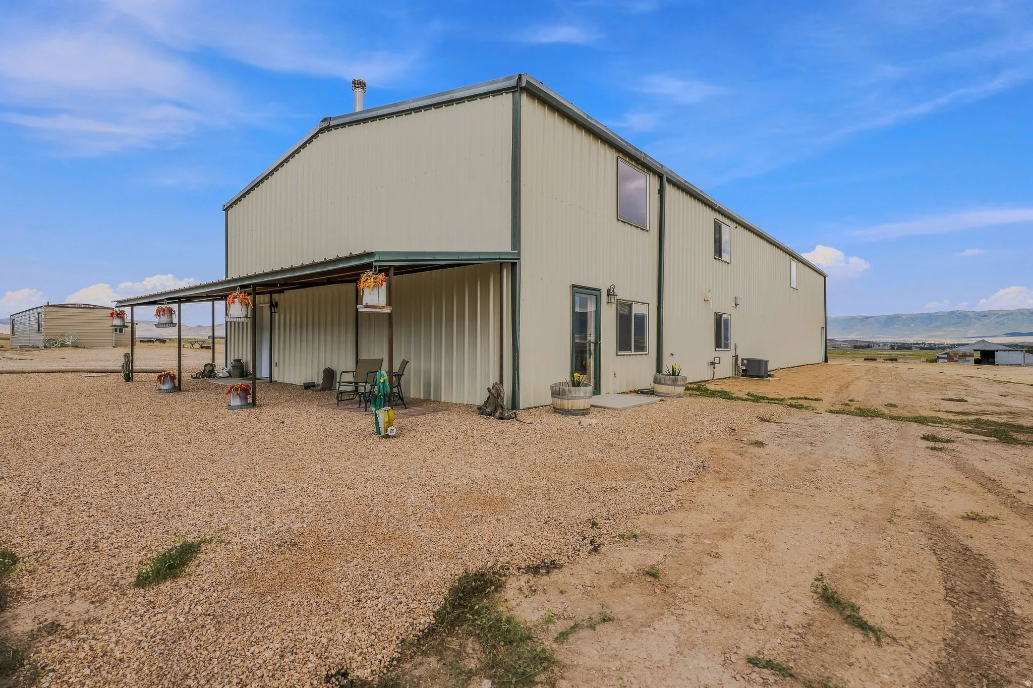 Two-story exterior with corrugated metal siding, an extended covered patio, and multiple windows
