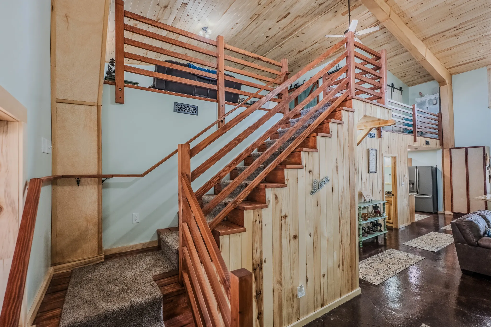Exposed wood-finish ceiling, wood-paneled walls, wood-finish staircase with matching railings, and a lofted area