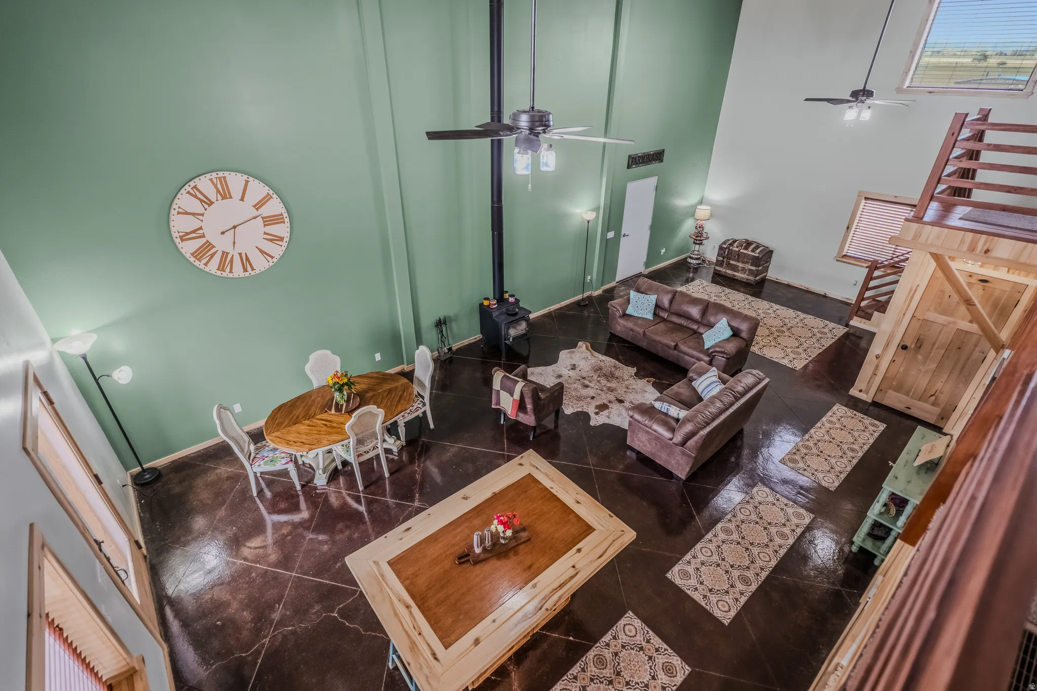 Vaulted ceilings, dark-toned flooring, integrated wood-burning stove, ceiling fans, and a loft area
