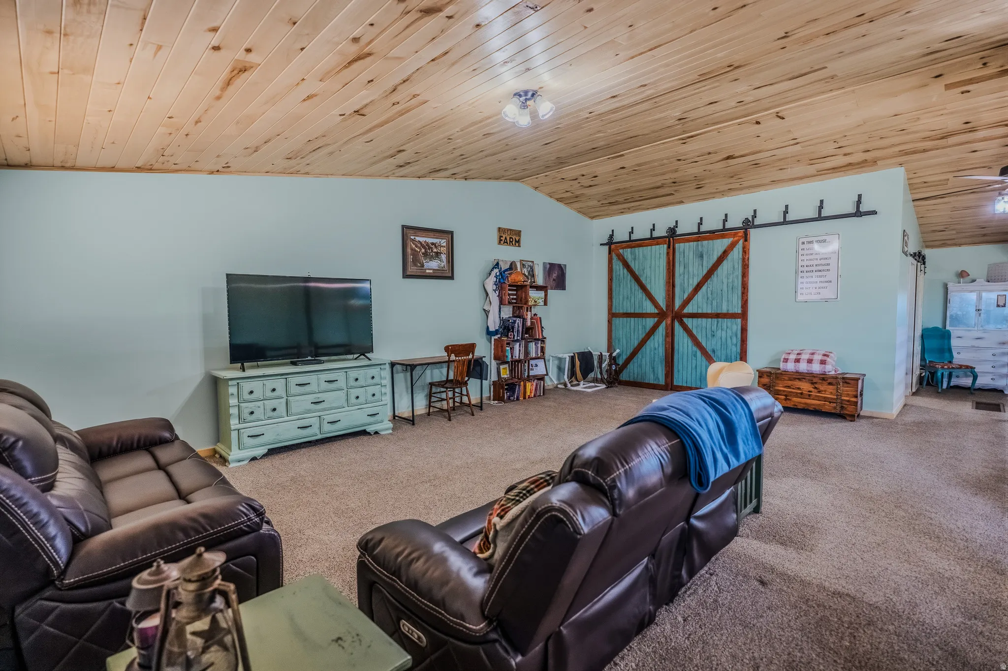 Vaulted wood-paneled ceiling, light blue painted walls, carpeted flooring, and a barn door entry