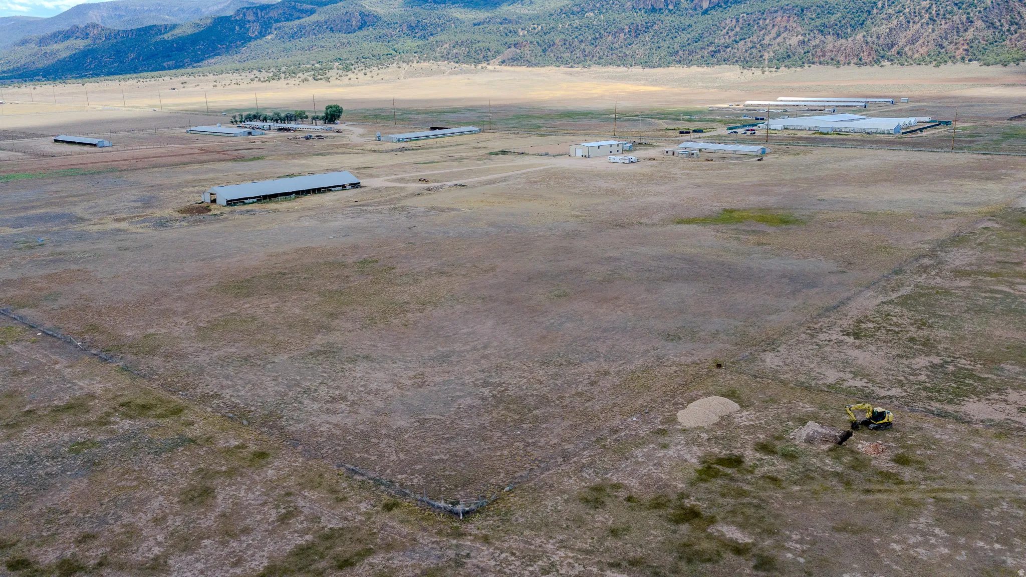 Expansive property featuring several large industrial structures and a mountainous backdrop