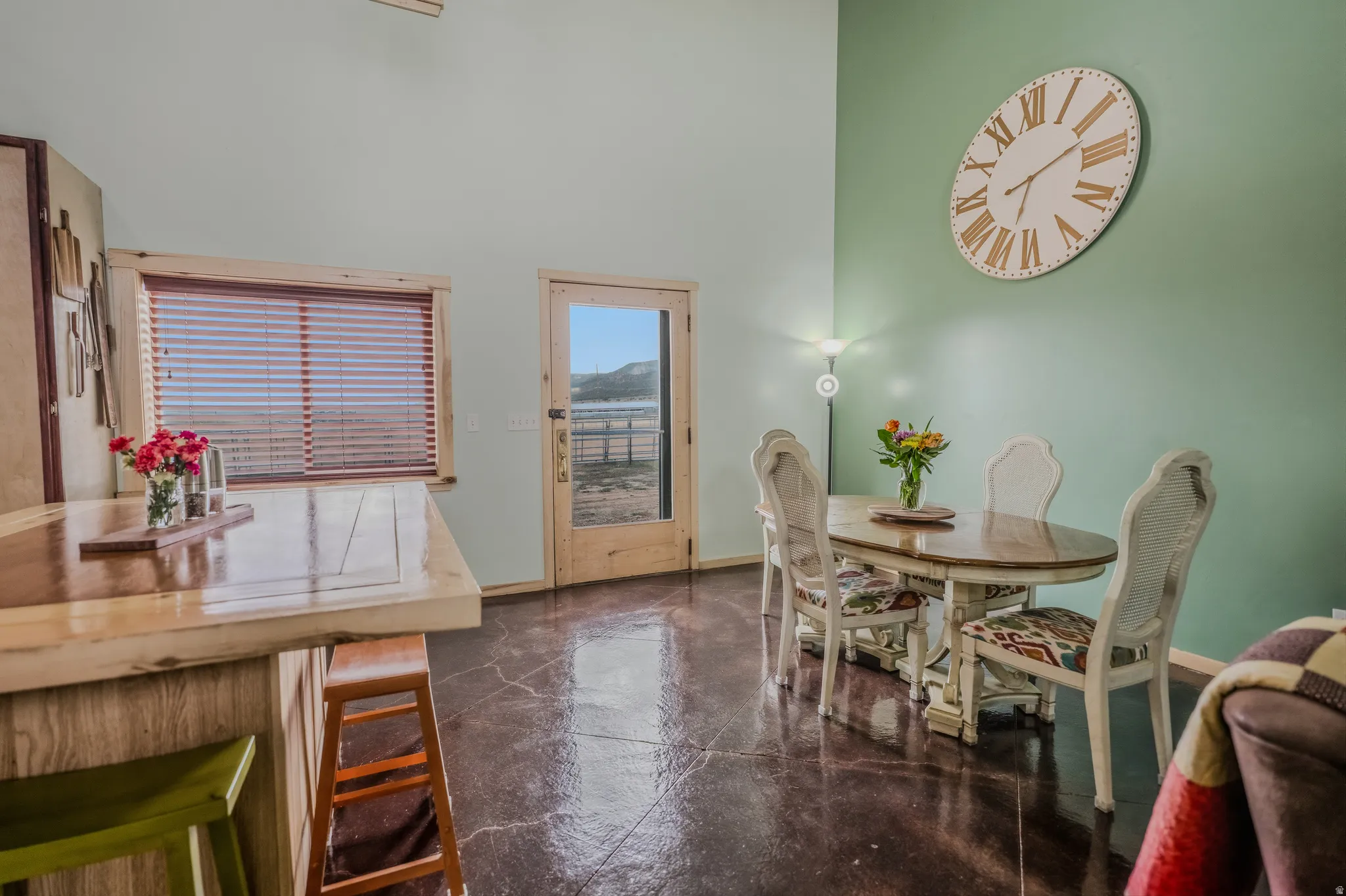 Vaulted ceiling, wood-finish flooring, wood-framed window with blinds, wood-framed door with glass panel, and light-toned walls