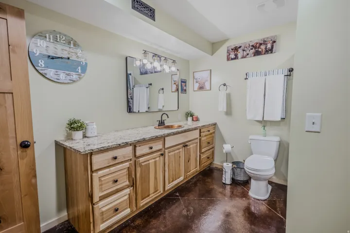 Long wood-finish vanity with an undermount sink, granite-style countertop, and dark-framed mirror