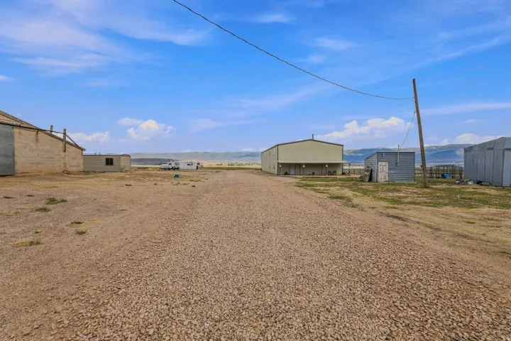 Gravel driveway leading to multiple outbuildings, including a large metal-sided structure with a covered porch