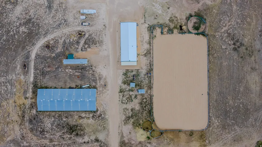 Expansive land featuring multiple structures, a large sand arena, and a smaller circular pen