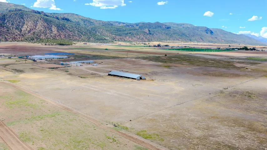 Expansive open land with a large agricultural building and distant mountain scenery