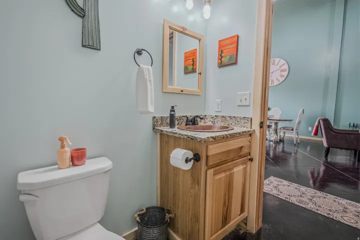 Wood vanity with a granite countertop, copper vessel sink, and a wood-framed mirror