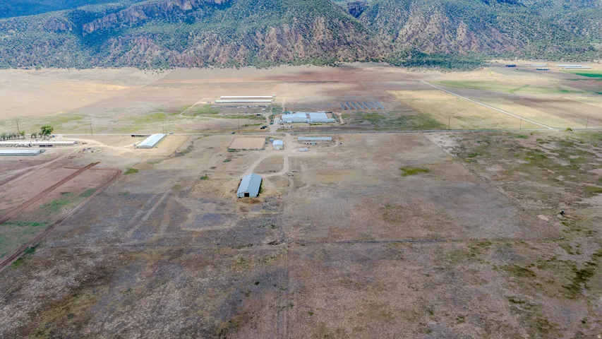 Expansive rural property featuring multiple outbuildings, open fields, and distant mountainous terrain