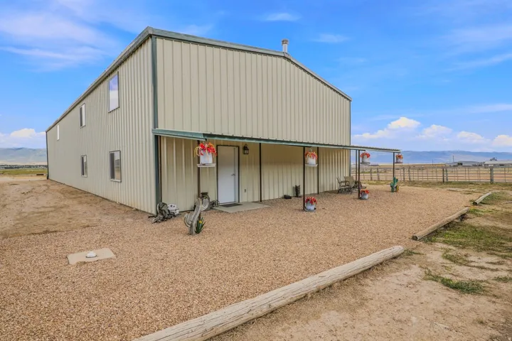 Corrugated metal siding structure with a covered front porch and gravel landscaping