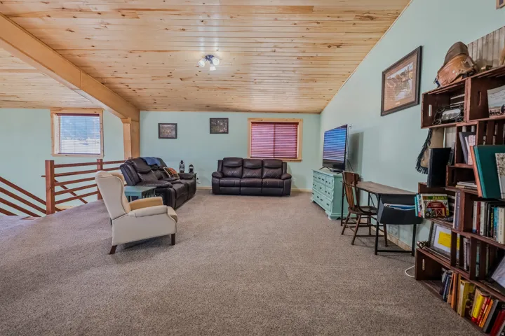 Vaulted wood-paneled ceiling with exposed beams, light blue wall paint, and carpeted flooring