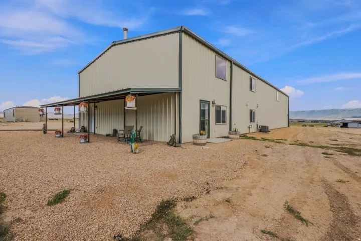 Two-story exterior with corrugated metal siding, an extended covered patio, and multiple windows