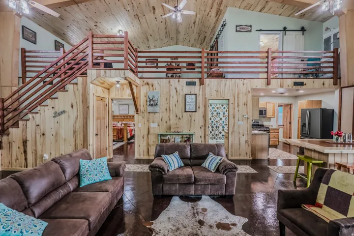 Vaulted wood-finish ceilings, wood-finish walls, wood-finish flooring, and a wood-finish staircase with railing