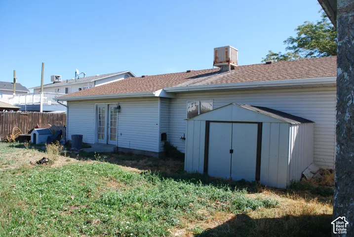 Exterior siding with a shingled roof, featuring a storage shed and a patio
