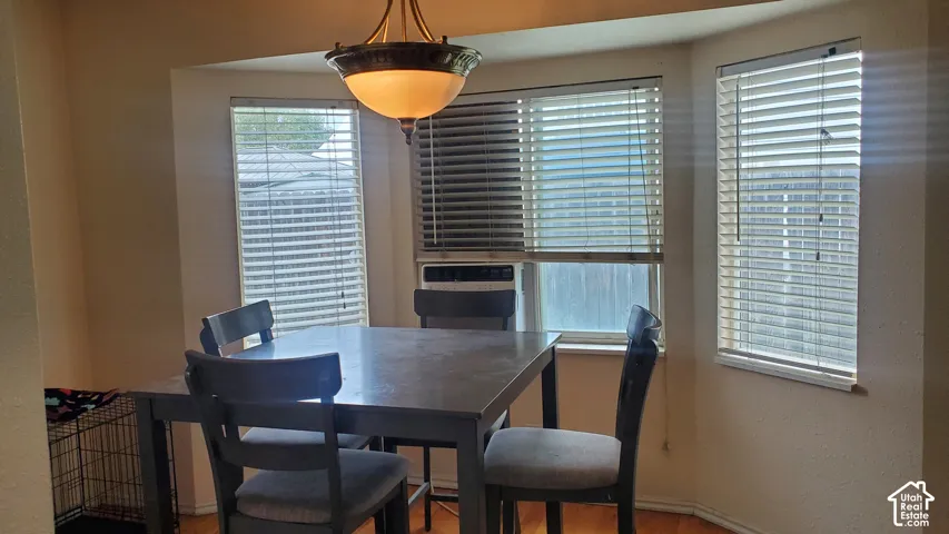 Bay window with Venetian blinds, wood-finish flooring, and a ceiling-mounted light fixture