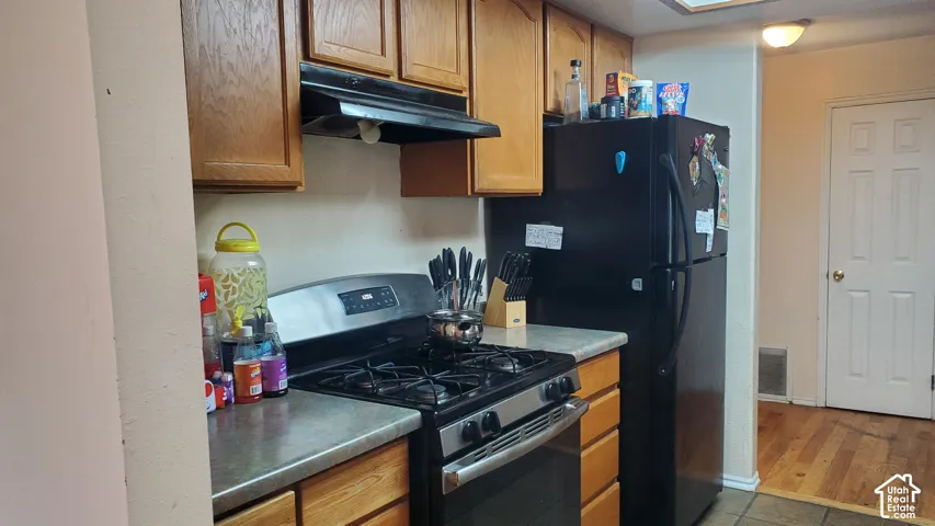 Kitchen featuring wood cabinetry, stainless steel gas range, and a black refrigerator