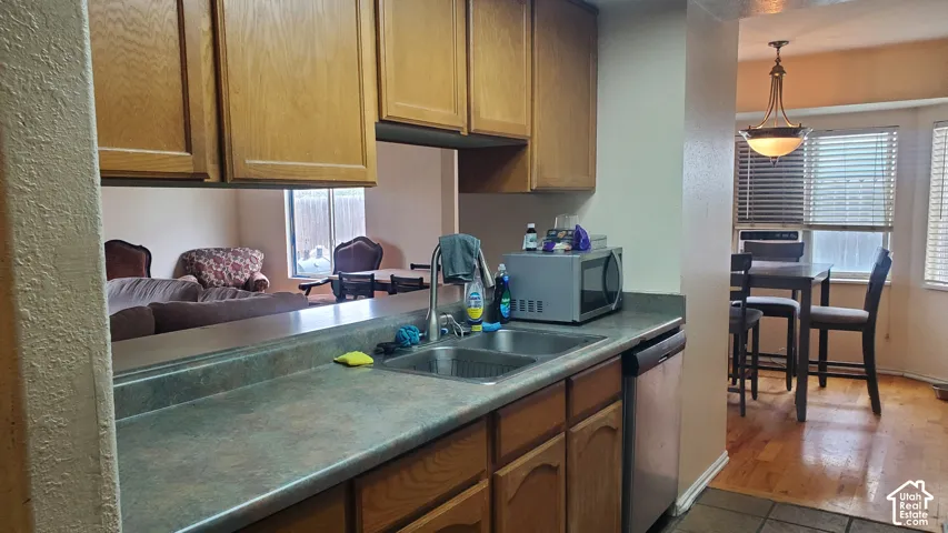 Kitchen with wood-finish cabinetry, a double basin stainless steel sink, and a built-in dishwasher