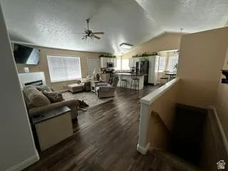 Open-concept living space featuring wood-finish flooring, a contemporary fireplace, and a ceiling fan