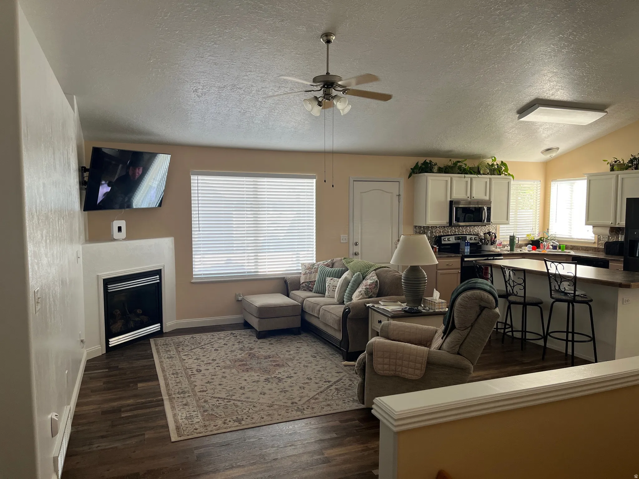 Living area featuring wood-finish flooring, a corner fireplace, and a ceiling fan