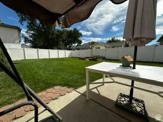 Expansive lawn area with a white privacy fence and a concrete patio