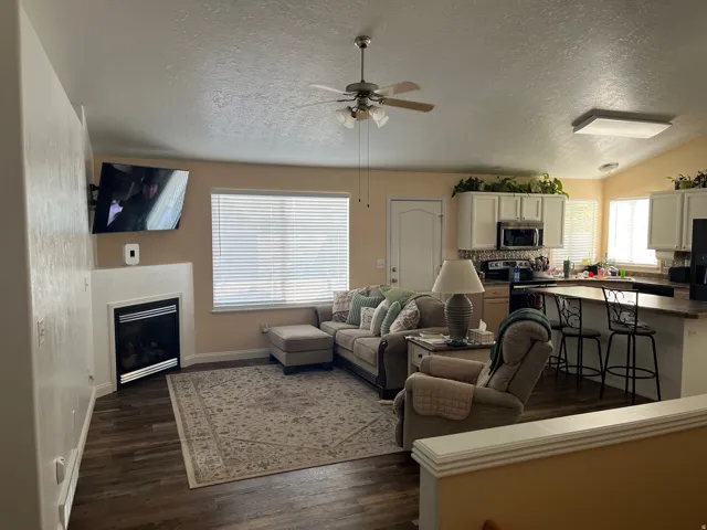 Living area featuring wood-finish flooring, a corner fireplace, and a ceiling fan
