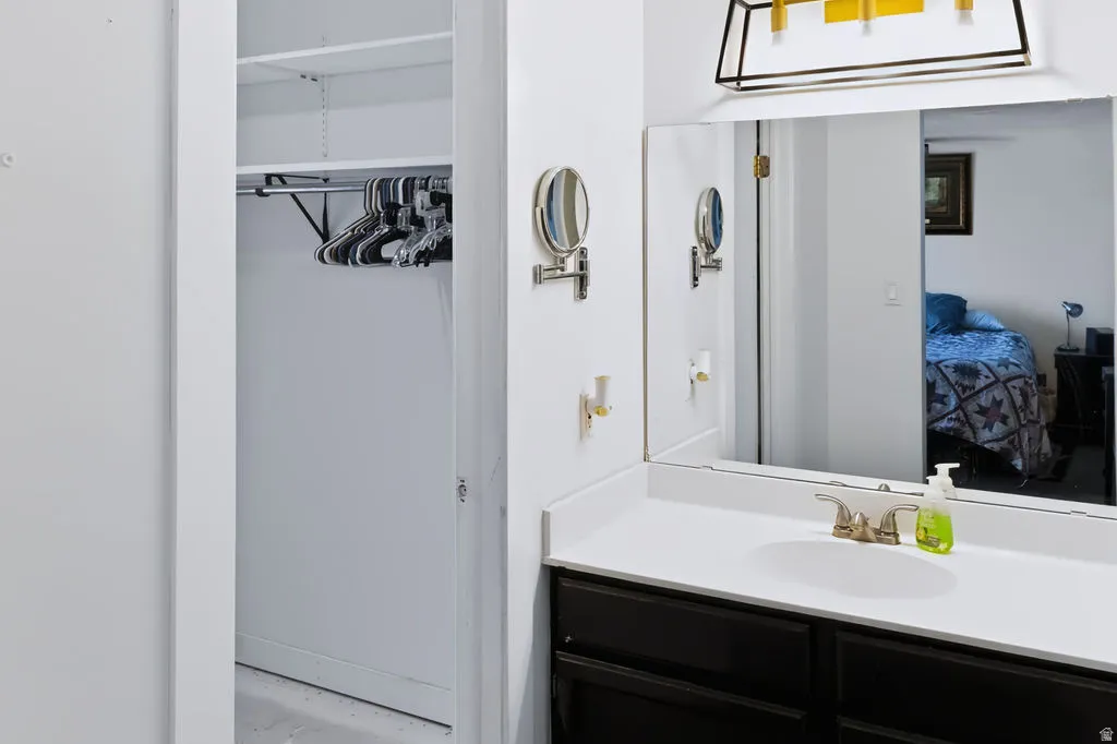 Vanity with an integrated sink, brushed nickel faucet, large wall-mounted mirror, and dark-finish cabinetry