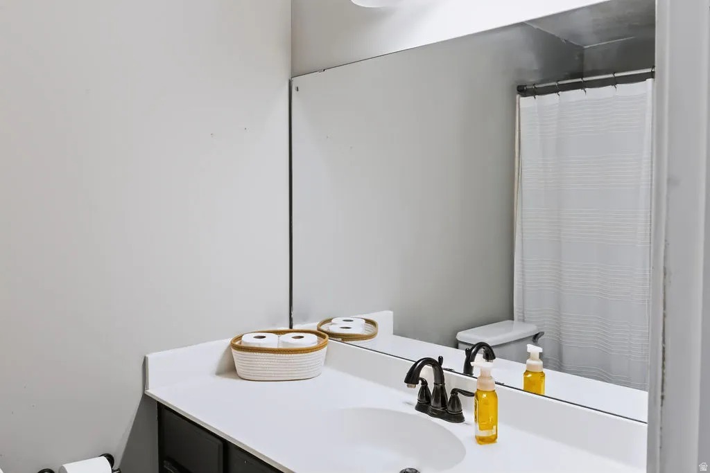 Integrated vanity with a white countertop and undermount sink, dark-finish cabinetry, and a dark-finish faucet