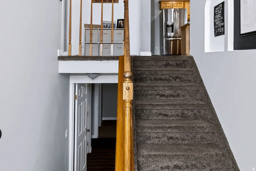 Carpeted staircase with wood-finish handrail and spindles