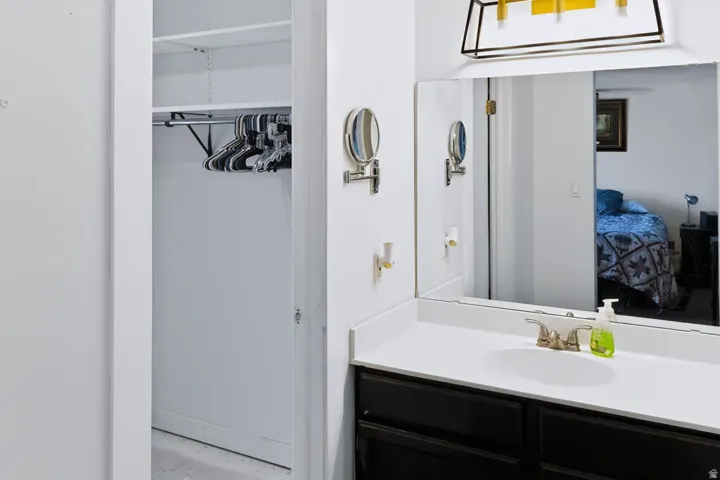Vanity with an integrated sink, brushed nickel faucet, large wall-mounted mirror, and dark-finish cabinetry
