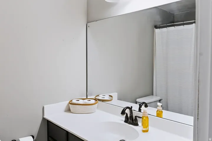 Integrated vanity with a white countertop and undermount sink, dark-finish cabinetry, and a dark-finish faucet