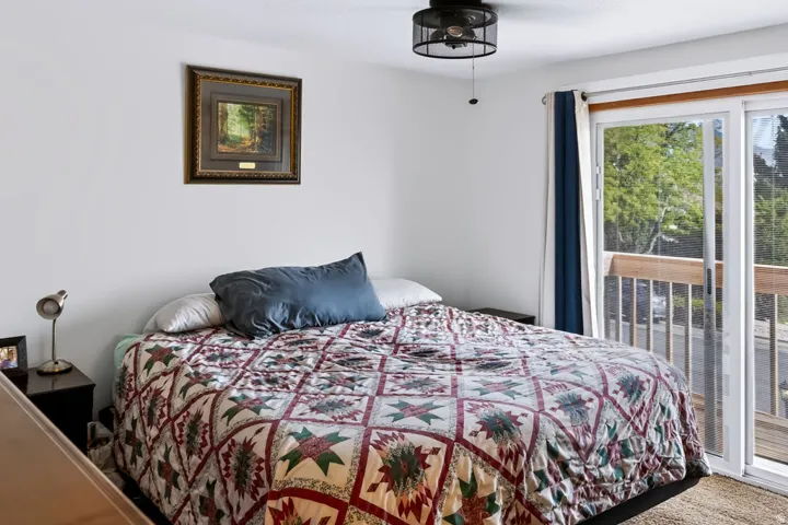White walls, black ceiling fan with mesh enclosure, and sliding glass door with a balcony