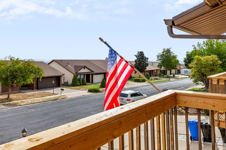 Wood-finish railing with metal spindles, brown gutters and soffit, and asphalt street