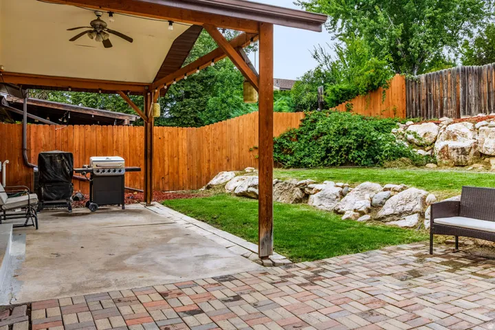 Covered patio with an exposed wood beam structure and a ceiling fan