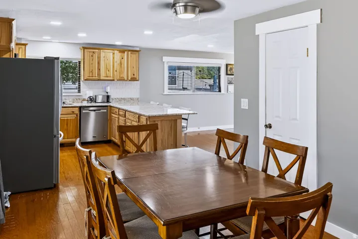 Kitchen and dining area featuring wood-finish flooring, light wood cabinetry, white subway tile backsplash, and light-colored countertops