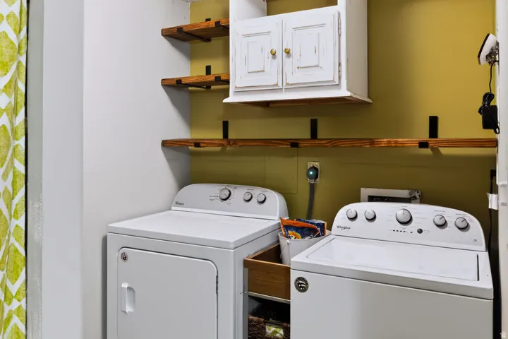 White wall-mounted cabinetry, wood-finish floating shelves, and a built-in laundry appliance area