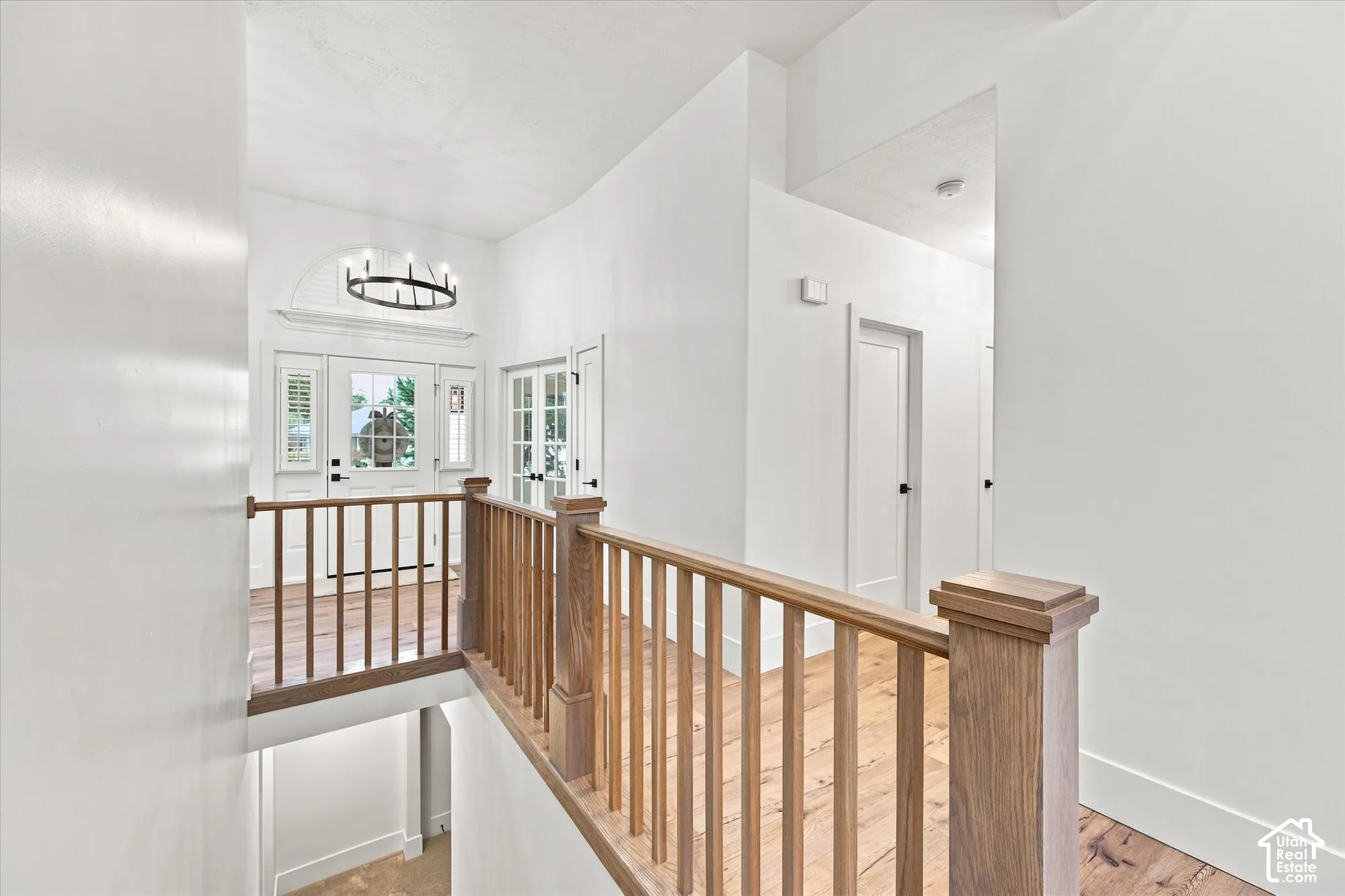 Hardwood flooring throughout, natural wood railing, white paneled doors, and an arched transom window