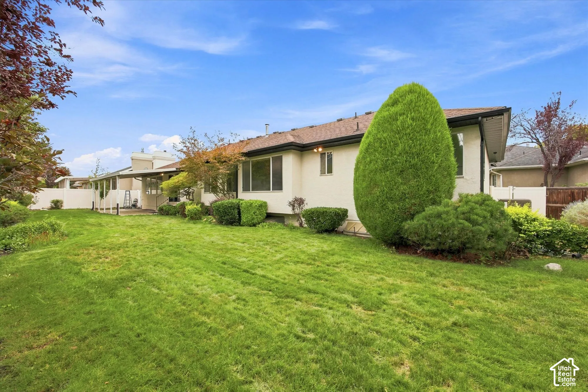 Expansive green lawn with mature landscaping and a covered patio area