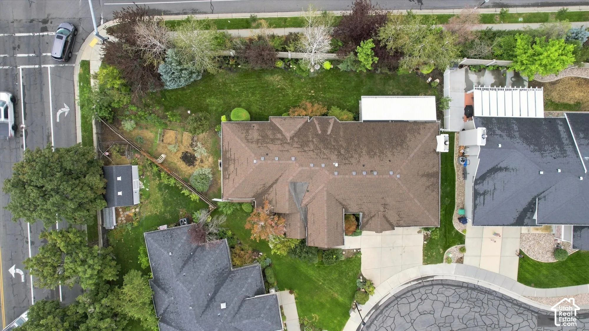Expansive lot featuring mature trees, a detached storage shed, paved driveway, and established landscaping