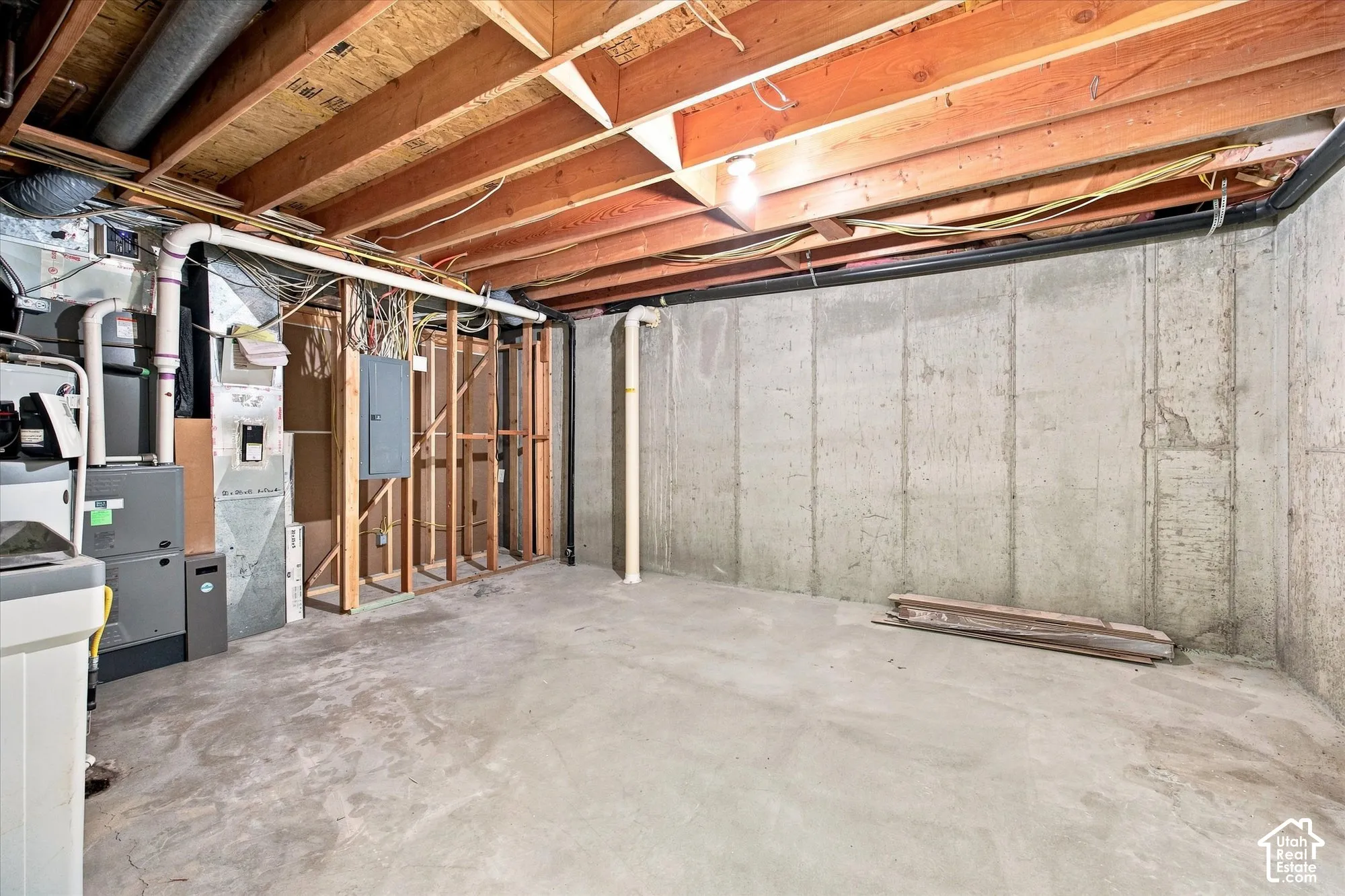 Unfinished basement featuring exposed wood joists, concrete flooring, and exposed concrete walls