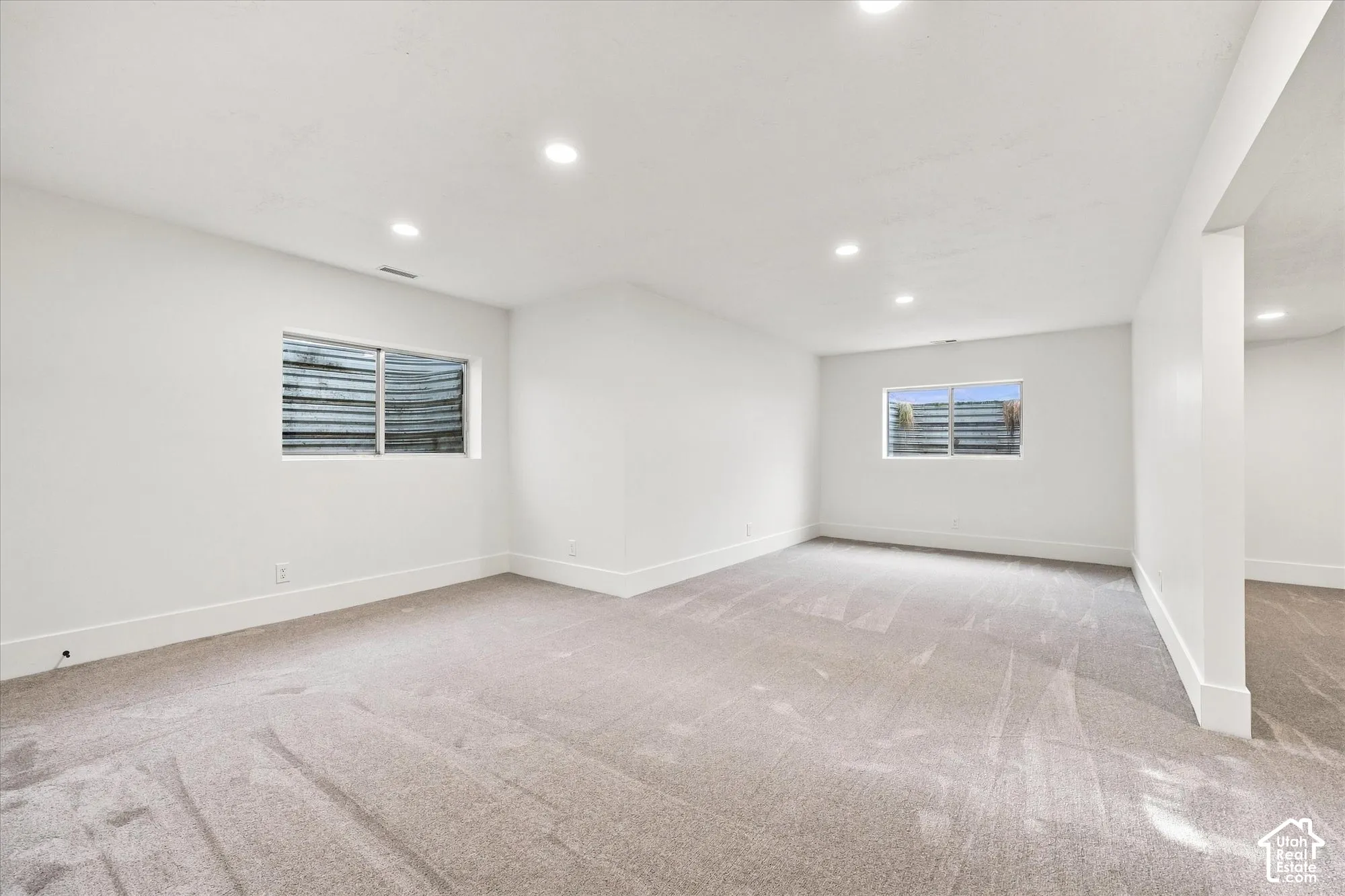 Recessed lighting illuminates the carpeted floor and white walls