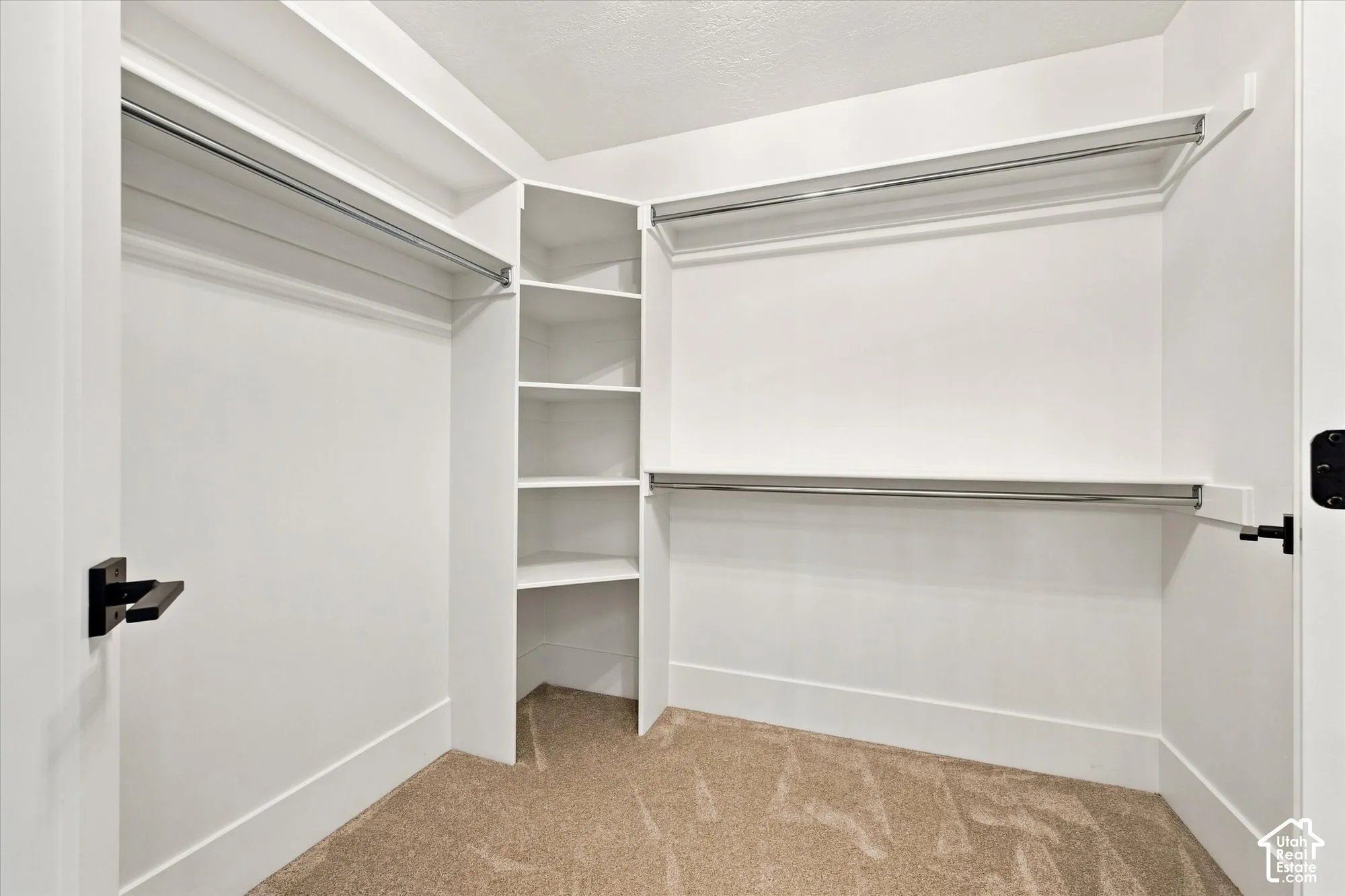 Built-in shelving, multiple hanging rods, and neutral carpet flooring