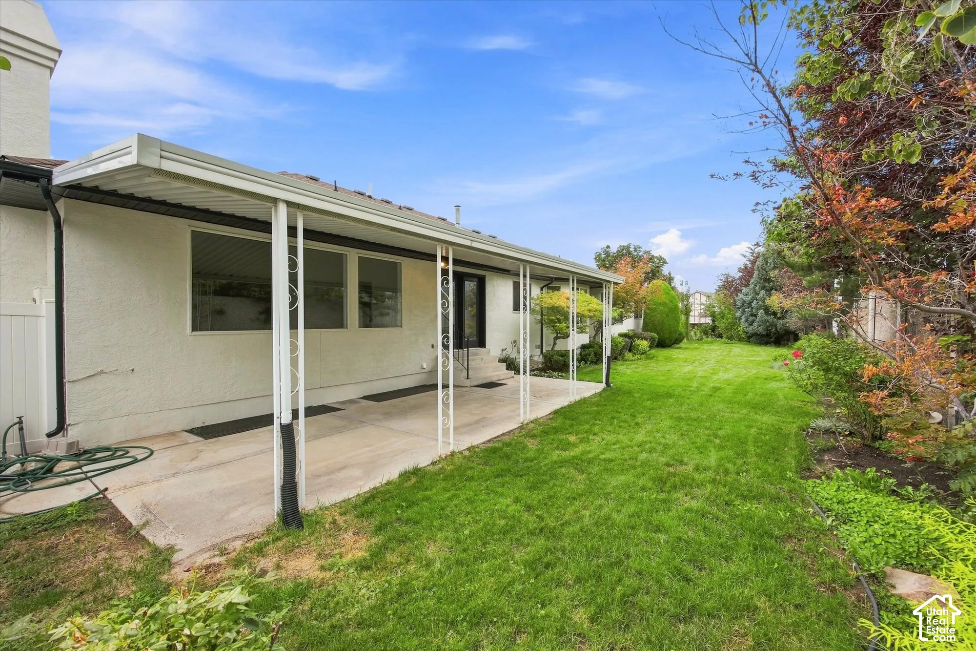 Expansive backyard featuring a concrete patio, covered patio structure, and a large grassy area